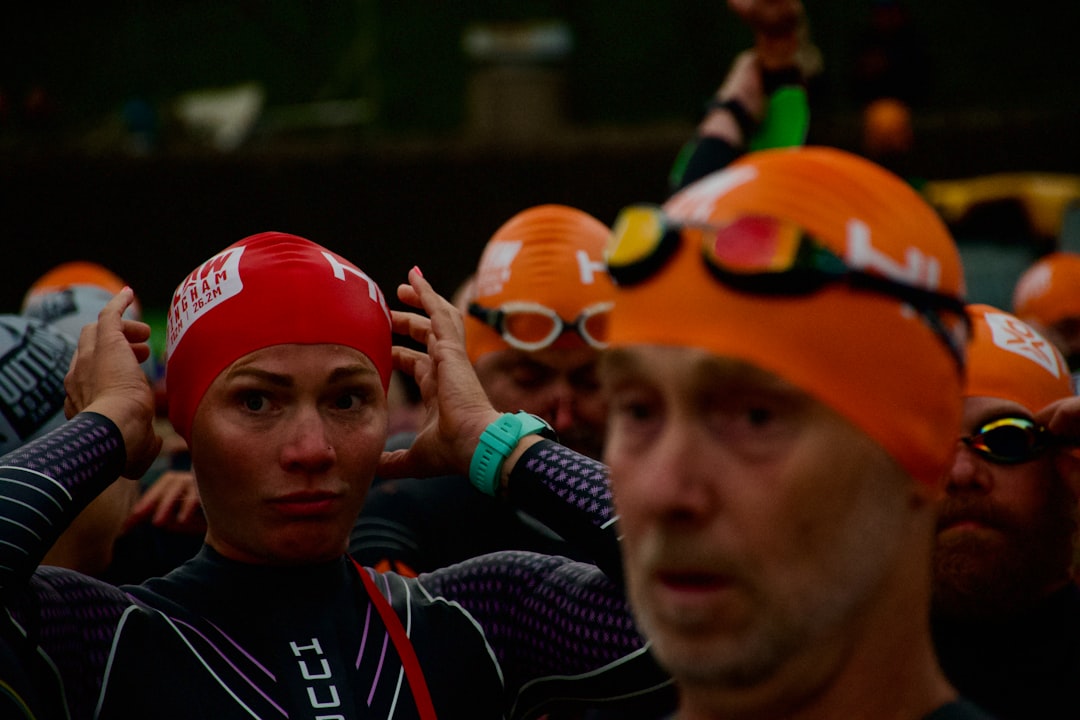 Swimmers in orange and red caps preparing for race.
