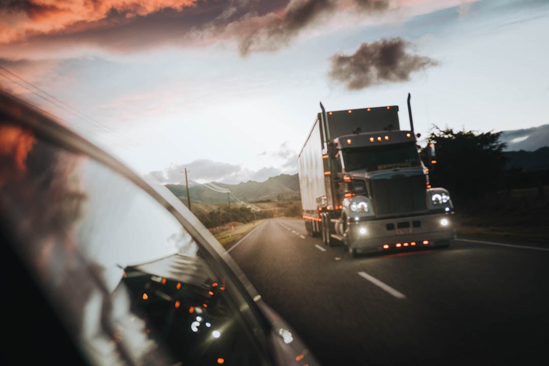 A semi truck driving on a highway under a warm orange sky